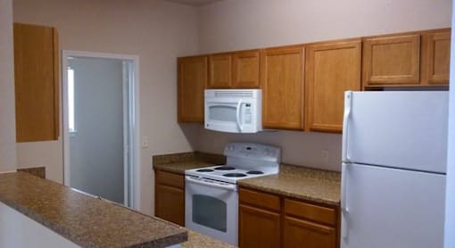 A kitchen with a white refrigerator, white oven, and white microwave.