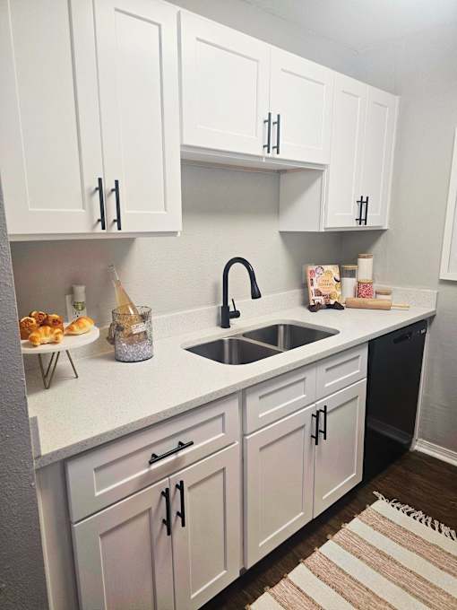 a kitchen with white cabinets and a sink and a rug