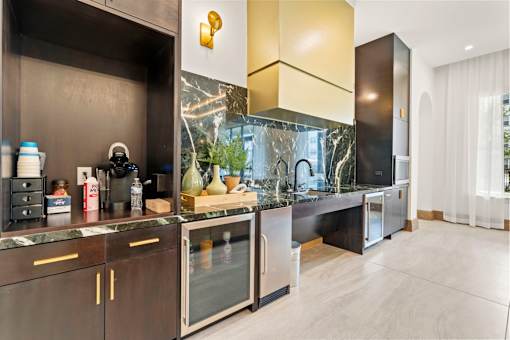 A modern kitchen with dark wood cabinets and a marble countertop.