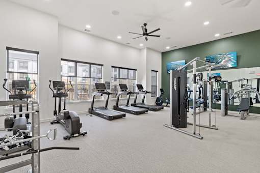 A spacious gym with a variety of equipment including treadmills, elliptical machines, and weight machines.