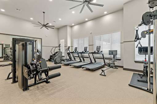 A spacious gym with a variety of equipment including treadmills, weight machines, and a squat rack.