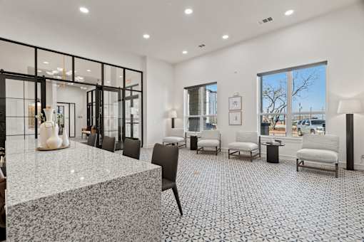 A spacious waiting area with a marble floor and black chairs.