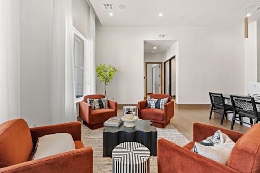 A living room with brown chairs and a black and white ottoman.