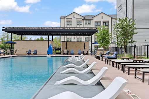 A pool with a blue umbrella and chairs.