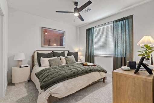 A bedroom with a bed, nightstand, and a ceiling fan.