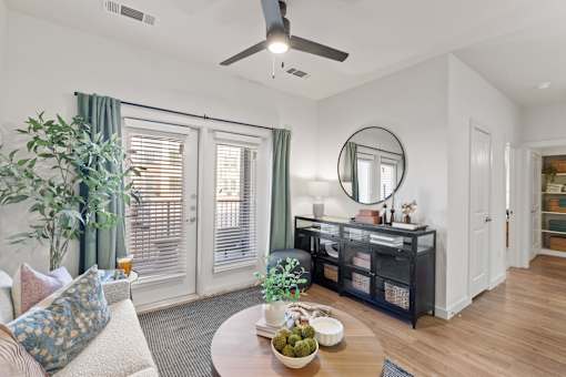 A living room with a couch, a table, a plant, and a mirror.