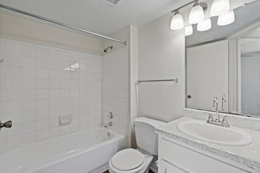 A white bathroom with a toilet, sink, and bathtub.