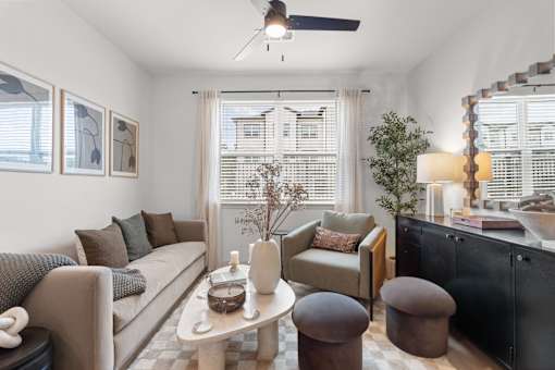 A living room with a beige couch, a brown armchair, a white coffee table, and a black cabinet.