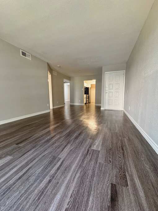 an empty living room and dining room with wood flooring