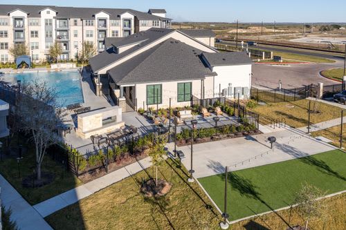 A large white building with a pool in front of it. at Enclave on Ross Apartments, Texas, 78617