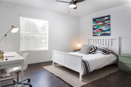 A bedroom with a bed, desk, and chair.