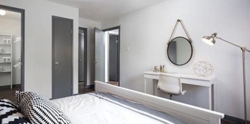 A bedroom with a bed, desk, and mirror.