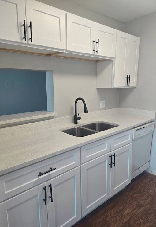 an empty kitchen with white cabinets and a sink