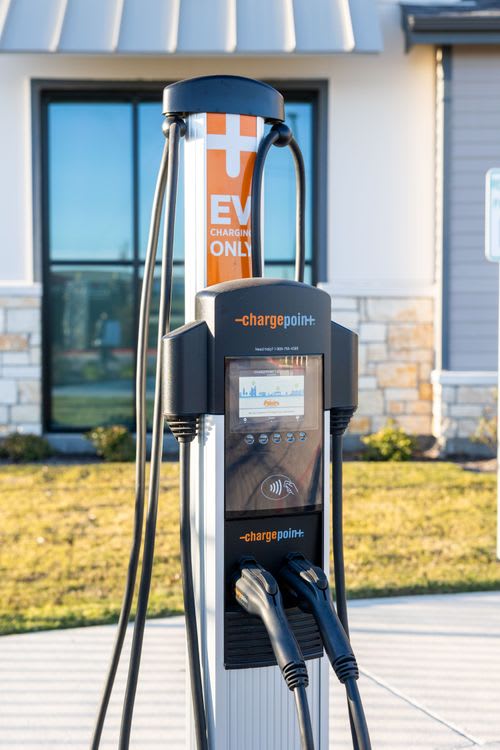 A ChargePoint electric vehicle charging station sits on a sidewalk. at Enclave on Ross Apartments, Del Valle