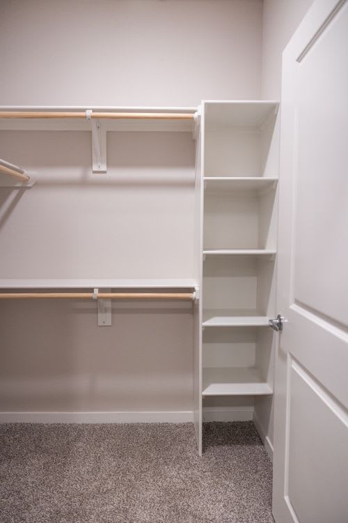 A white closet with shelves and a door. at Enclave on Ross Apartments, Del Valle, TX