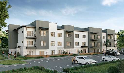 A modern apartment complex with cars parked in front.