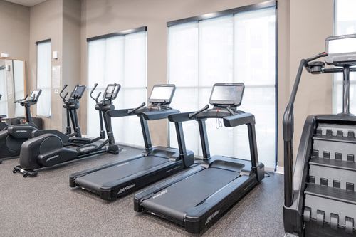 A gym with treadmills and elliptical machines. at Enclave on Ross Apartments, Del Valle, TX, 78617