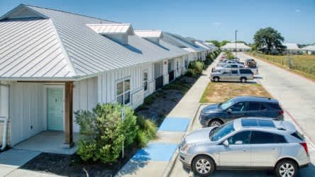 A row of houses with cars parked in front.