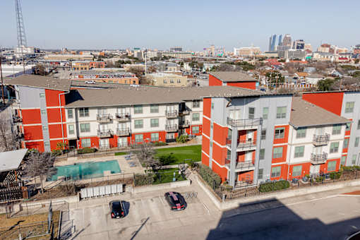 A red and white apartment complex with cars parked in the driveway.