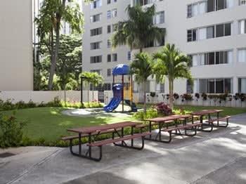 a park with a playground and picnic tables in front of a building