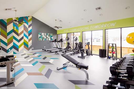 A gym with a variety of equipment and a colorful wall.