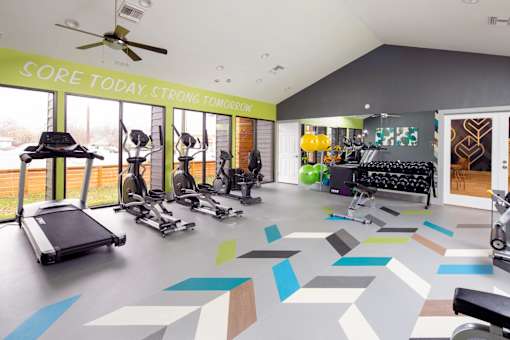A gym with a variety of equipment including treadmills, exercise bikes, and weights.