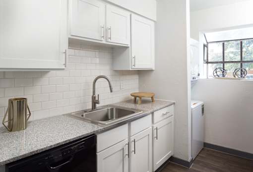 A kitchen with white cabinets and a granite countertop.