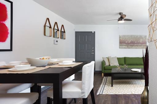 A dining room with a table set for two and a green couch.