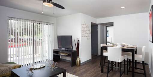 A modern living room with a black coffee table and a white dining table.