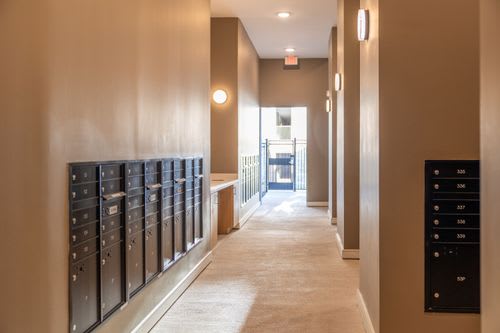 A hallway with a series of mailboxes on the left side. at Enclave on Ross Apartments, Texas