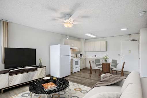 A modern living room with a flat screen TV, a black coffee table, and a white sofa.