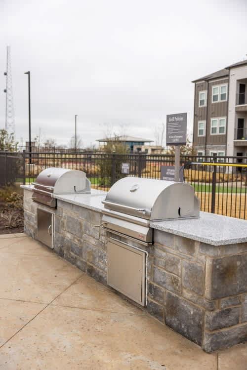 A stone wall with a mailbox and a grill on top.