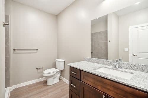 A bathroom with a toilet, sink, and mirror.