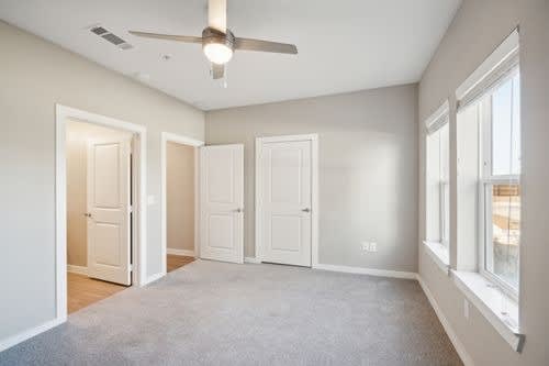 A room with a ceiling fan and three doors.