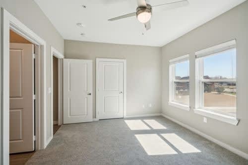 A room with a ceiling fan and three doors.