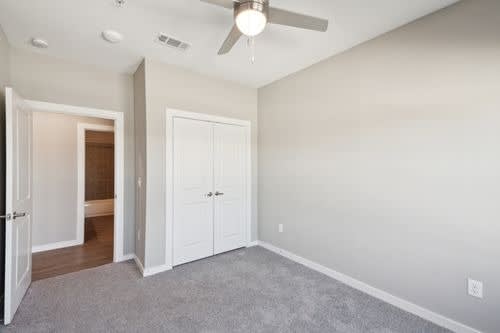 A room with a ceiling fan and two doors.