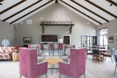 A room with a pink chair in the foreground and a kitchen in the background.