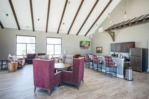 A modern open plan living and kitchen area with wooden floors and a high ceiling.