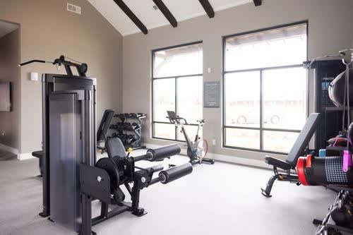 A gym with a variety of equipment including a squat rack, a leg press machine, and a rowing machine.