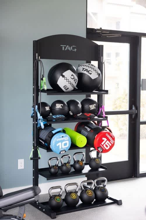 A black shelf with a variety of fitness equipment including kettlebells and a jump rope.