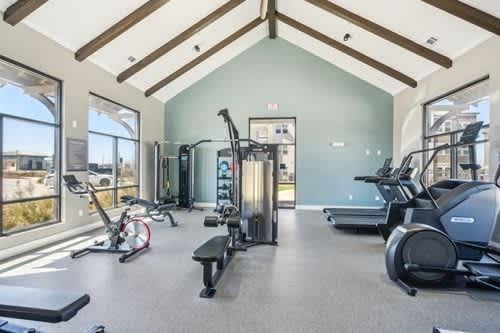 A spacious gym with a variety of equipment including treadmills, stationary bikes, and weight machines.