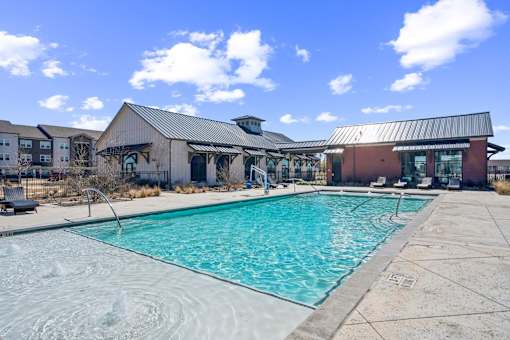 A large outdoor swimming pool with a metal roofed building in the background.