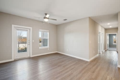 A spacious room with wood flooring and a ceiling fan.