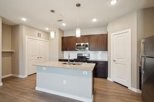 A kitchen with a white island and wooden cabinets.