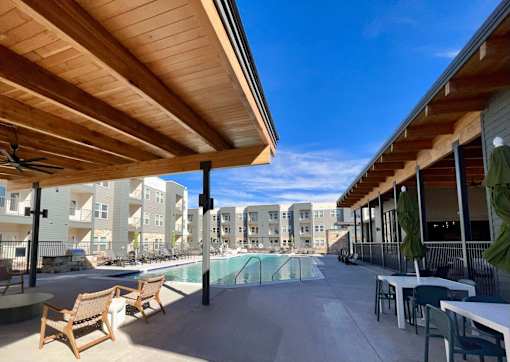 A wooden patio with chairs and a table overlooking a pool.