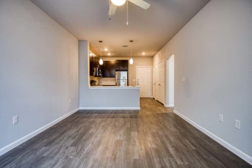 a living room with a kitchen and a ceiling fan