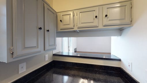 a kitchen with white cabinets and black counter top and a window