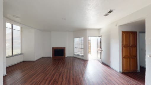 an empty living room with wood floors and a fireplace
