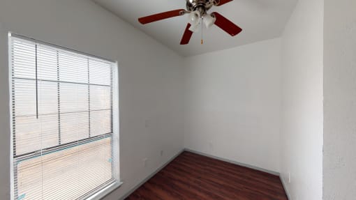 an empty bedroom with a large window and a ceiling fan