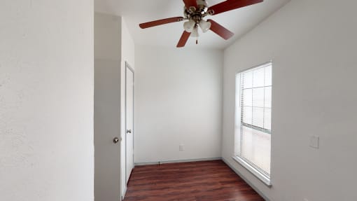 an empty room with a ceiling fan and a window